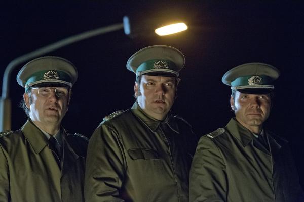 Bild 1 von 3: Peter Arndt (Rainer Bock), Harald Schäfer (Charly Hübner) und Burkhard Schönhammer (Max Hopp) versuchen sich vom Dach eines Postenhäuschens einen Überblick zur Lage vor dem Grenzübergang zu verschaffen.