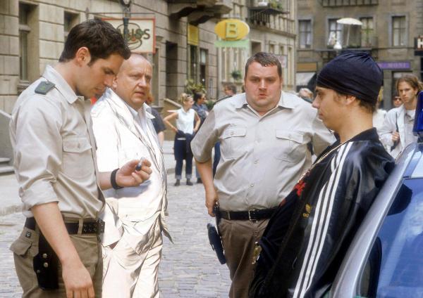Bild 1 von 3: Im Bild: Tobias (Manuel Witting, li.) verhaftet Milan (Richard Kropf, re.), der in Tobias Viertel Crack geraucht hat. Als Lutz (Udo Kroschwald, 2.v.li.) noch lebte, hat es sowas in dieser Gegend nicht gegeben. Müller (Christoph-Hagen Dittmann, 2.v.re.) kommt von seiner 'Zwischenmahlzeit'.