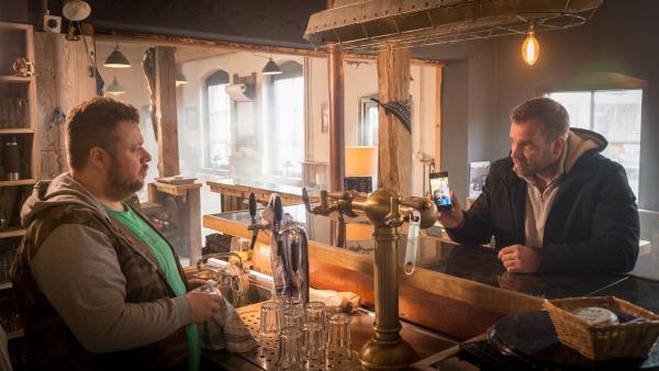 Bild 1 von 7: Kommissar Pöhlmann (Dominic Booer, r.) befragt Wirt Arne Weiss (Till Butterbach, l.) in seiner Gaststätte nach einem Rottweiler. Arne Weiss behauptet, sich nicht sicher zu sein, ob es sein Hund ist. Auch sonst zeigt er sich wenig kooperativ. Was hat er zu verbergen? Wie steht er zu der Toten und warum leugnet er, dass der Rottweiler sein Hund ist? Pöhlmann ist sich sicher, hier stimmt etwas nicht.