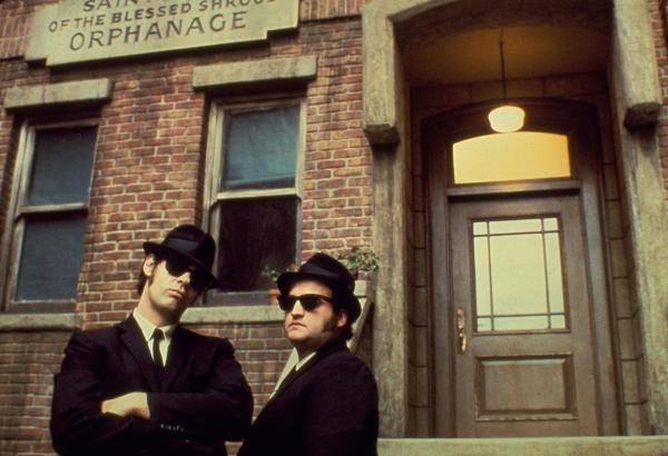 Bild 1 von 9: Schwarze Anzüge, schwarze Hüte, schwarze Sonnenbrillen und natürlich ein schwarzes Auto - so ziehen die Brüder Jake (John Belushi, r.) und Elwood Blues (Dan Aykroyd, l.) durch Detroit und hinterlassen eine Spur der Verwüstung hinter sich ...