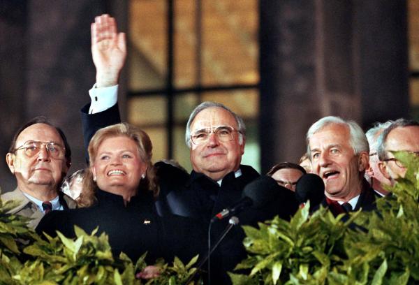 Bild 1 von 1: Wiedervereinigung: Bundeskanzler Helmut Kohl (M.) winkt am 3. Oktober 1990 zum Geläut der Freiheitsglocke von der Freitreppe des Berliner Reichstages. Links neben Kohl stehen Außenminister Hans-Dietrich Genscher und Hannelore Kohl, rechts von ihm Bundespräsident Richard von Weizsäcker.