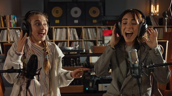 Bild 1 von 1: Lucy (Kensington Tallman, l.) und ihre Stiefmutter (Eleonora Facchini, r.) singen gemeinsam in einem Studio.