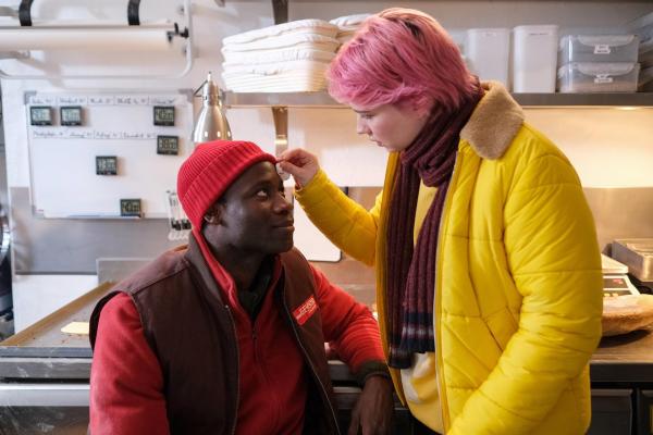 Bild 1 von 1: Im Bild: Das fühlt sich trotz Schmerzen gut an: Adika (Yann Mbiene) hat sich in der Backstube an der Stirn verletzt und wird von Pflegerin Tessa (Zoë Valks) professionell verarztet.