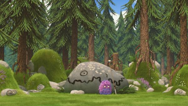 Bild 1 von 4: Strit sitzt vor einem bemalten Felsbrocken und guckt traurig.