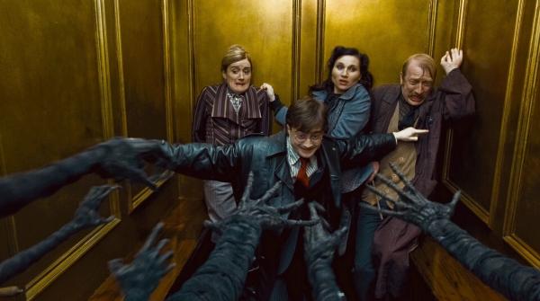 Bild 1 von 8: Daniel Radcliffe as Harry Potter standing with arms out, Sophie Thompson as Mafalda Hopkirk, Kate Fleetwood as Mary Cattermole and Steffan Rhodri as Reg Cattermole leaning back against wall behind him.