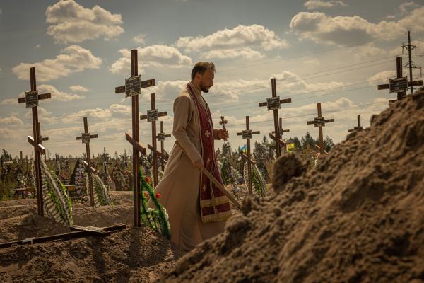 Bild 1 von 2: Ein Priester bestattet die ukrainischen Zivilisten, die 2022 von russischen Soldaten in Butscha ermordet wurden.