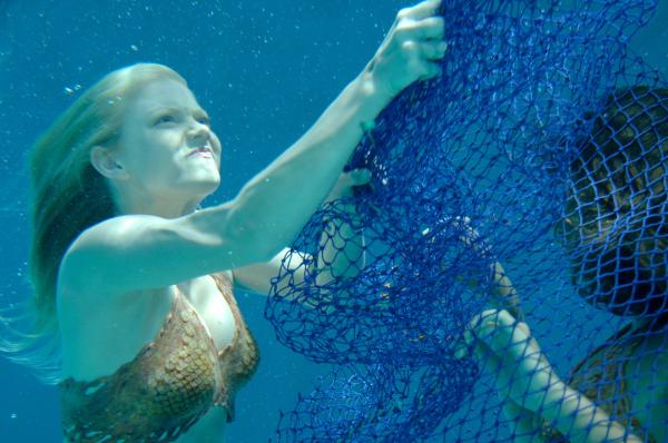 Bild 1 von 2: Cleo (Phoebe Tonkin, r.) hat sich bei ihrer Suche nach dem illegalen Schildkrötenfischer in einem Fischernetz verfangen. Sie wird von Rikki (Cariba Heine, l.) befreit.