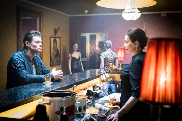 Bild 1 von 7: Galina Sorokina (Katerina Medvedeva, r.) hat Boris (Eugen Bauder, l.) zu sich bestellt. Sie möchte sich ein Bild von dem Mann machen, der ihre Mädchen zu ihren Terminen fährt.