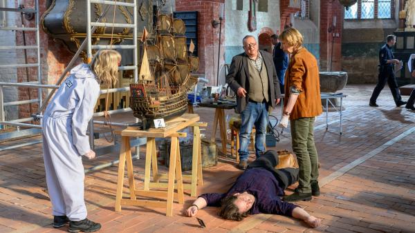 Bild 1 von 5: Erste Untersuchungen der Rechtsmedizinerin Dr. Helene Sturbeck (Katharina Blaschke, r.) ergeben, dass Sven Lundquist (Øystein Kloster, 2.v.r.) erschlagen wurde, gleich neben dem Modellschiff \