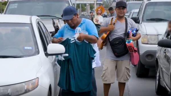 Bild 1 von 3: Straßenhandel am Grenzübergang: Zwei Männer nutzen den Stau, um Autofahrern Kleidung anzubieten.