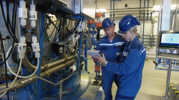 Bild 1 von 14: Im Bild: Fachkräfte bei Thermo Fisher Scientific vor einem chemischen Reaktor zur Medikamentenproduktion.