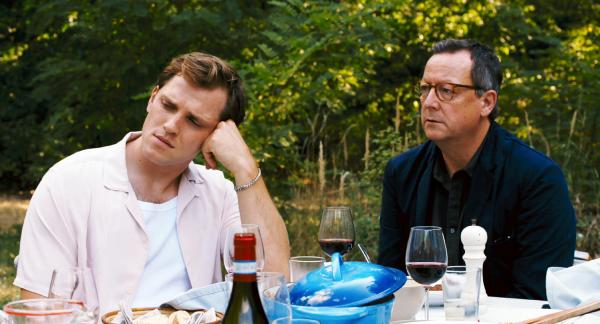 Bild 1 von 5: Lektor Helmut (Matthias Brandt, r.) ist zu der Gruppe der vier jungen Menschen dazugestoßen. Am Tisch mit Devid (Enno Trebs, l.) hören sie gebannt Nadjas Vortrag von einem Gedicht zu.