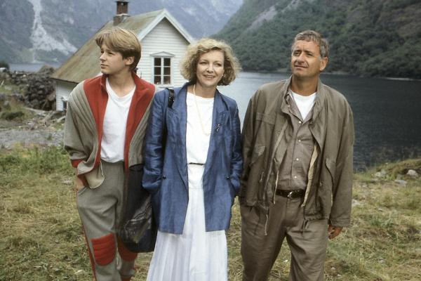 Bild 1 von 3: Chiefdriller Peter Pacard (Peter Bongartz, r.) hatte mit seiner Frau Katrin (Gila von Weitershausen, M.) und seinem Sohn Patrik (Hendrik Martz, l.) einen ruhigen Urlaub in einem norwegischen Fjord vor. Lachse wollte er fangen, mit seiner Frau Tennis spielen und mit dem Jungen den Modellhubschrauber fliegen lassen. Statt dessen gerieten sie in eine turbulente Agentenschlacht um eine geheimnisvolle Formel, so dass ihr Haus von den Sicherheitsbehörden besetzt wird und sie ziemlich ratlos das Geschehen verfolgen, das sie selbst immer mehr bedroht.