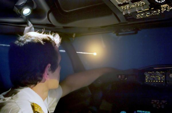 Bild 1 von 4: Ein Pilot betrachtet durch das Cockpit seines Flugzeugs die Flugbahn eines Asteroiden.