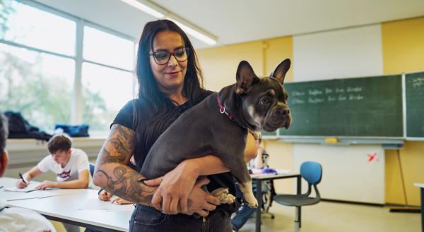 Bild 1 von 3: Lehrerin Julia Molter nimmt Hund Ruby mit in ihre besondere Klasse, wo keiner bisher auf dem herkömmlichen Weg einen Abschluss geschafft hat. Ruby hilft, mit den Schüler:innen noch schneller eine Verbindung aufzubauen.