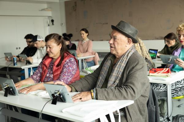 Bild 1 von 15: Die Schüler*innen Gülmira Bishek (Ruzica Hajdari, l.) und Walter König (Hans-Martin Stier, r.) hören aufmerksam zu und staunen über die technische Ausstattung der Bildungslandschaft.