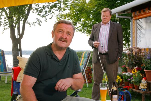 Bild 1 von 3: Hat Dauercamper Harald Meierling (Ferry Oellinger, l.) im Streit seinen Wohnwagennachbarn umgebracht? Rosenheim-Cop Hartl (Michael A. Grimm, r.) befragt ihn.