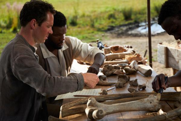 Bild 1 von 15: Ausschnitt Spielszene: Rennen um die größten Knochen. Expeditionsleiter Werner Janensch und Edwin Hennig suchen zwischen 1909 und 1913 auf den Tendaguru-Hügel, im heutigen Tansania, erfolgreich nach Dinosaurierknochen. Es konnten 230 Tonnen Knochen gefunden werden. Ausgelöst durch einen Zufallsfund eines Einheimischen.