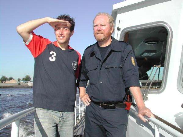 Bild 1 von 1: Willi (links) mit einem Zollbeamten auf dem Zollschiff im Hamburger Hafen. Mit ihnen ist Willi unterwegs, um einen Bananenfrachter aus Kolumbien auf Schmuggelware zu durchsuchen.