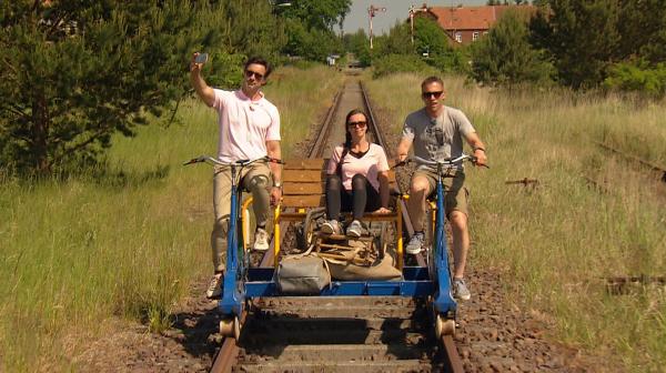 Bild 1 von 3: Moderator Marco Schreyl (links), Steffi Herrmann und Nicky Herrmann (rechts) transportieren ihr Faltboot auf einer Draisine.