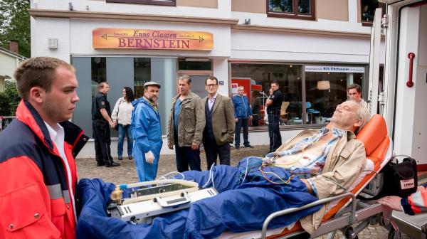 Bild 1 von 8: Im Bild: Ein brutaler Überfall auf ein Bernstein-Schmuckgeschäft in Scharbeutz: Weil der Bernsteinschleifer Enno Claasen (Hans-Heinrich Hardt, r.) ungeplant früher vom Strand zurückkommt, überrascht er zwei Einbrecher auf frischer Tat und wird dabei von einem Schuss lebensgefährlich verletzt. Finn Kiesewetter (Sven Martinek, M.), Lars Englen (Ingo Naujoks, 2.v.r.) und Dr. Henning Strahl (Christoph Tomanek, 4.v.r.) ermitteln.