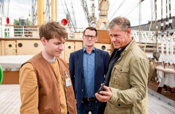 Bild 1 von 1: Im Bild: Finn (Sven Martinek, r.) und Lars (Ingo Naujoks, M.) konfrontieren Neeles Arbeitskollegen Timo (Filip Januchowski, l.) mit belastendem Videomaterial. Er war Neele und Pascal in der Tatnacht gefolgt.