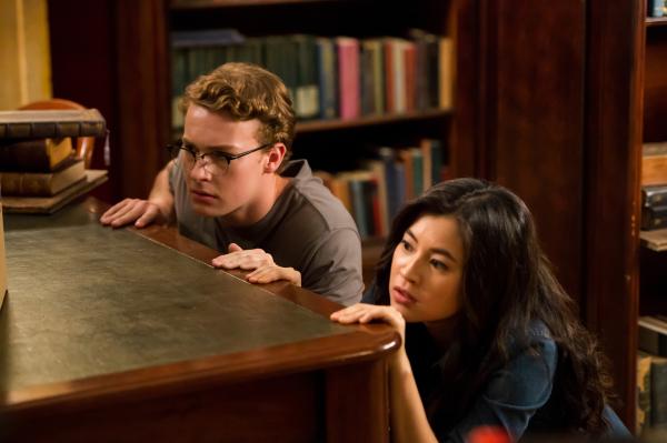 Bild 1 von 5: Kyra (Kimie Tukakoshi, rechts) hat Peter (Jamie Carter, links)  heimlich mit in die Bibliothek genommen. Als sie Geräusche hören, verstecken sie sich. Sie wollen nicht entdeckt werden.