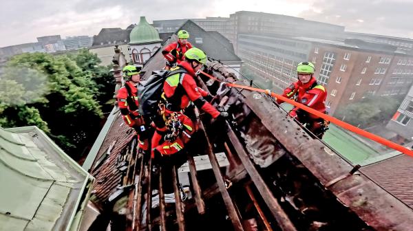 Bild 1 von 2: Einsatz in 20 Metern Höhe: Bei einem Dachstuhlbrand bereiten die Höhenretter die Sicherungen für ihre Kollegeninnen und Kollegen vor.