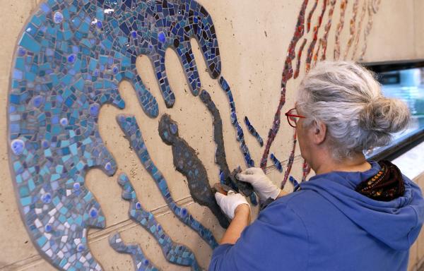 Bild 1 von 4: Tanja Lebski verfugt und finalisiert das Mosaikkunstwerk für das Hallenbad einer Schule.