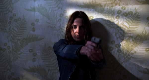 Frau mit Waffe in der Hand zielt