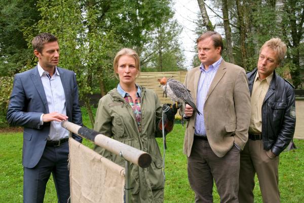 Bild 1 von 2: Die Rosenheimer Ermittler Hansen (Igor Jeftic, l.), Hartl (Michael A. Grimm, 2.v.r.) und Mohr (Max Müller, r.) recherchieren bei Sandra Holzinger (Stefanie von Poser, 2.v.l.).