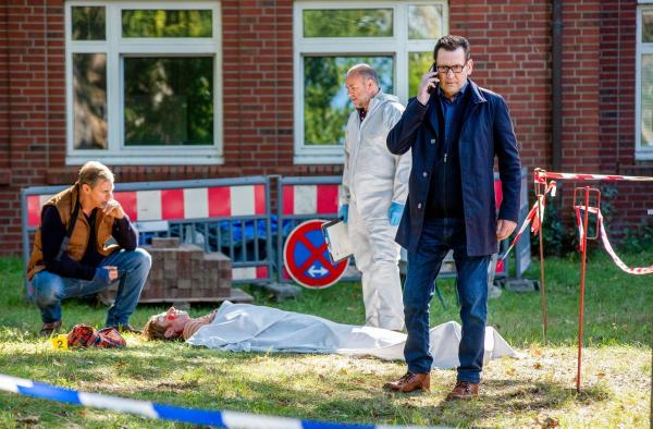 Bild 1 von 1: Im Bild: Der Krankenhausclown Fidan Petrov (Philipp Boos, liegend) liegt erschlagen im Hinterhof der Klinik. Die Kommissare Finn Kiesewetter (Sven Martinek, l.) und Lars Engel (Ingo Naujoks, r. mit Christoph Tomanek, 2.v.r.) ) finden heraus, dass der Tote ein Betrüger war.