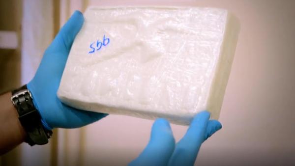 Bild 1 von 3: Grenzbeamte zeigen ein sichergestelltes Drogenpaket, das mit einer Prägung der \