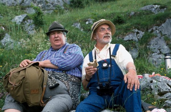 Bild 1 von 4: Endlich eine Rast bei der Wanderung zur Bergspitze in den Alpen. Herr Paschulke (Helmut Krauss, l.) denkt gleich ans Essen, aber Peter (Peter Lustig, r.) macht Paschulke auf die wunderbare Pflanzen- und Tierwelt aufmerksam.