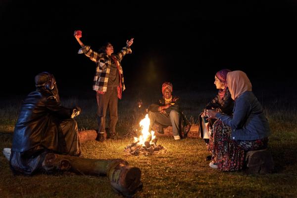 Bild 1 von 6: Am Lagerfeuer schöpfen Momtaz (Lucie Shorthouse, l.), Saira (Sarah Kameela Impey, 2.v.l.), Bisma (Faith Omole, M.), Ayesha (Juliette Motamed, 2.v.r.) und Amina (Anjana Vasan, r.) neue Kraft für den Soundsmash-Vorentscheid.