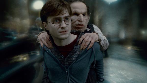 Bild 1 von 7: Daniel Radcliffe as Harry Potter carrying Warwick Davis as Griphook
