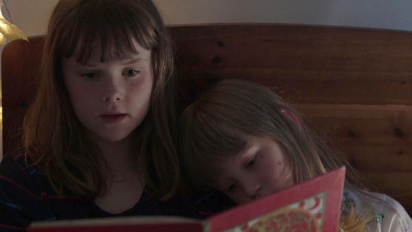 Bild 1 von 3: Agnes (li., Synne Asplund) lässt Elsa (re., Maya Anna Hansen Frølich) in ihr Bett und gemeinsam lesen sie noch.