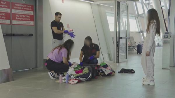 Bild 1 von 2: Zollbeamte durchsuchen am Flughafen das Gepäck einer Reisenden - zwischen den Kleidungsstücken könnten sich verbotene Substanzen oder Gegenstände verbergen.