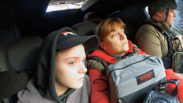Bild 1 von 5: Natalya (M.) und ihre Tochter Elena (l.) haben in dem Keller einer Schule Schutz vor den russischen Angriffen gesucht. Nach sechs Monaten geben sie auf und verlassen Marinka .
