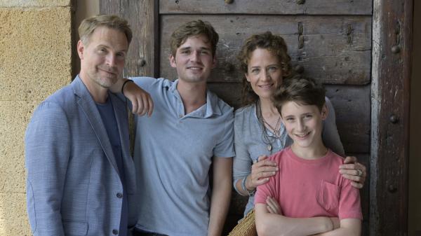 Bild 1 von 15: Vor einer dunklen Tür auf einer Terrasse steht Maja und ihre Familie. Von links:  ihr Ex-Mann Thorsten (Janek Rieke), daneben ihr 17-jähriger Sohn Anton (Henry Horn). Maja (Regula Grauwiller) hat ihrem jüngeren Sohn Erik (Levis Kachel) liebevoll die Hände auf die Schultern gelegt.