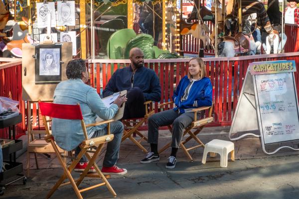 Bild 1 von 3: Ava (Hannah Einbinder. r.) und Marcus (Carl Clemons-Hopkins, M.) geben sich auf dem Jahrmarkt gegenüber einem Zeichner (Peter Holden, l.) als Paar aus - und erkennen dabei, wie viel sie tatsächlich gemeinsam haben.