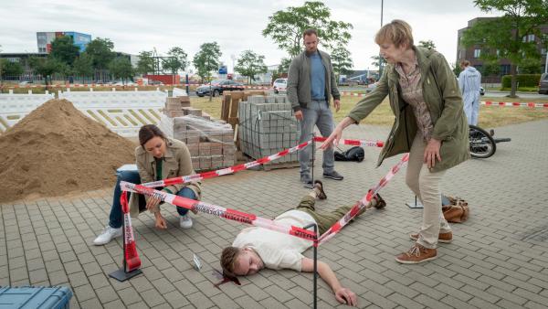 Bild 1 von 7: In der Nähe eines Logistikunternehmens liegt die Leiche von Christian Weber (Johannes Emig, M.). Kommissarin Karoline Joost (Nike Fuhrmann, l.), Kommissar Lars Pöhlmann (Dominic Boeer, 2.v.r.) und Dr. Helene Sturbeck (Katharina Blaschke, r.) müssen nun herausfinden: Wer hat den Projektleiter erschlagen? Und was ist die Tatwaffe? Etwa einer der Pflastersteine von der Baustelle?
