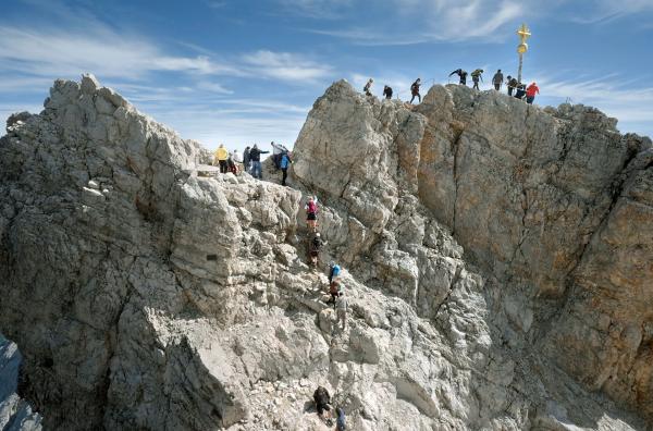 Bild 1 von 5: Das Gipfelkreuz der Zugspitze auf 2.962 Meter Höhe wird von Besuchern gerne mit Aufklebern beklebt ? und muss alle paar Jahre zur Reinigung und Restaurierung ins Tal geflogen werden.