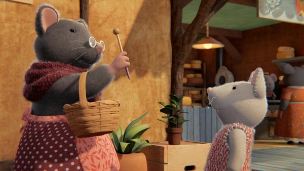 Bild 1 von 3: Oma Gouda (links) übergibt Julia (rechts) eine Stricknadel. Sie erzählt Julia, dass dies eine ganz besondere Stricknadel ist, die den Weg zu neuen Abenteuern im Mäusehaus weist.
