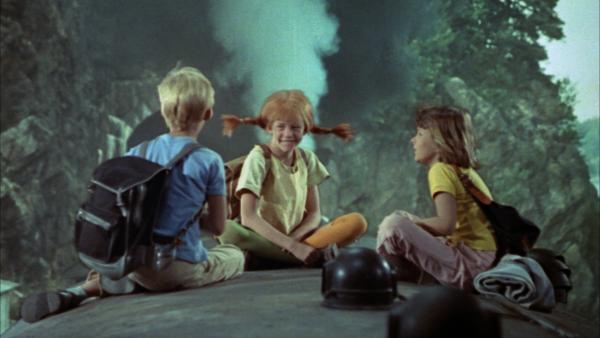 Bild 1 von 3: Die drei Ausreißer Tommy (Pär Sundberg, l.), Pippi (Inger Nilsson, M.) und Annika (Maria Persson, r.) sind von einer Brücke auf einen Zug gesprungen, um ihre Reise fortzusetzen.