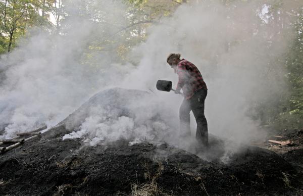 Bild 1 von 7: Köhler Max Geiselhart verdichtet mit dem Holzschlegel den Kohlenmeiler.