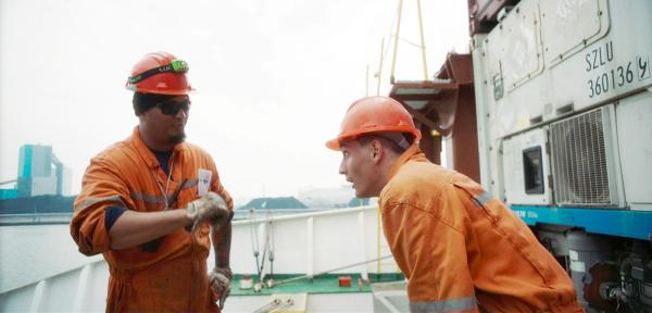 Bild 1 von 5: Arthur (Arthur Aliiev, re.) wird in die Arbeit auf dem Containerschiff eingewiesen.