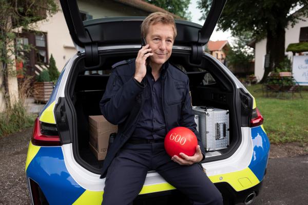 Bild 1 von 4: Polizeihauptmeister Mohr (Max Müller) möchte gerade das Dekomaterial für die anstehende Feier des Kegelvereins abliefern, als er stolz die extra angefertigte Kugel mit einer eingravierten \