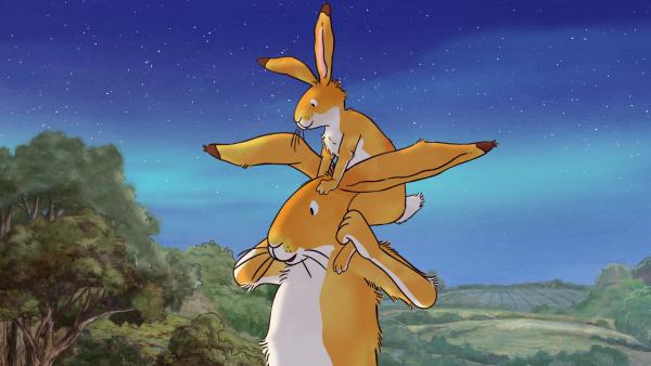 Bild 1 von 7: Der kleine braune Hase sitzt auf den Schultern des großen braunen Hasens.