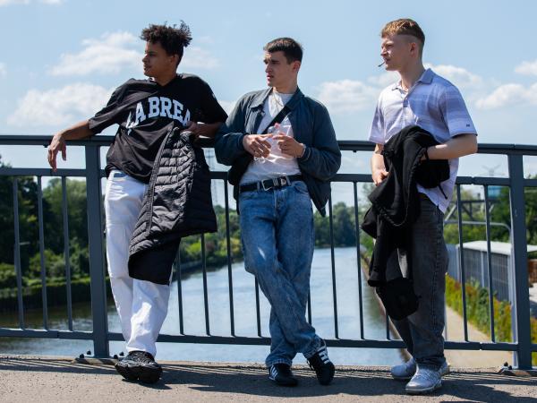 Bild 1 von 8: Juma (Vito Sack), Leo (Pablo Moreno) und Amir (Tommes Diallo) auf einer Brücke am frühen Morgen. Ein Moment der Orientierungslosigkeit nach einer durchfeierten Nacht.